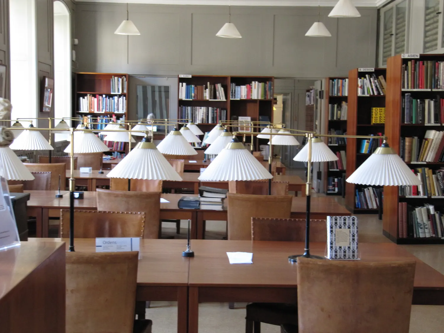 Biblioteka Designmuseum Danmark w Kopenhadze z drewnianymi regałami i lampami wiszącymi